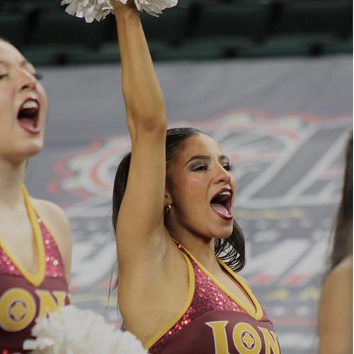 Iona Dance Team member cheering and holding her right pom-pom in the air.