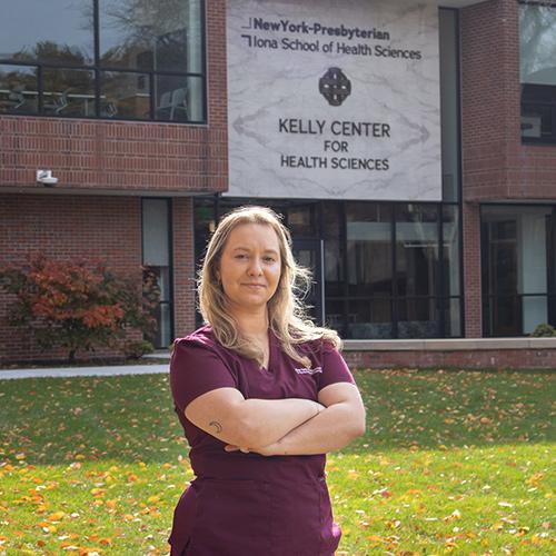 Hannah Griffin '26 posing and smiling in front of the New York-Presbyterian Iona School of Health Sciences Kelly Center for Health Sciences building on the Iona University Bronxville Campus.