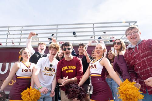 A group of enthusiastic Iona University students and cheerleaders posing together during an outdoor event.