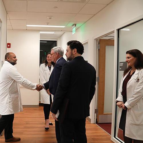 Health care leaders shake hands at the Kelly Center.