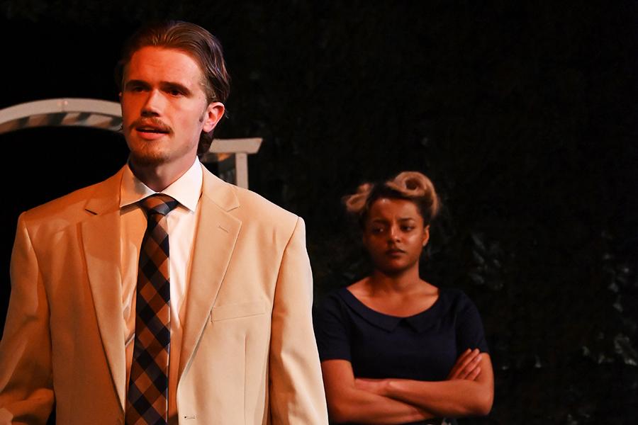 A man faces away from a woman and she crosses her arms.