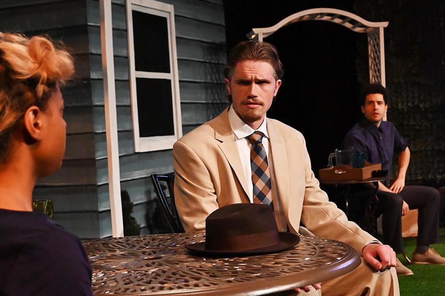 A man sits at a cafe table with a woman and they talk.