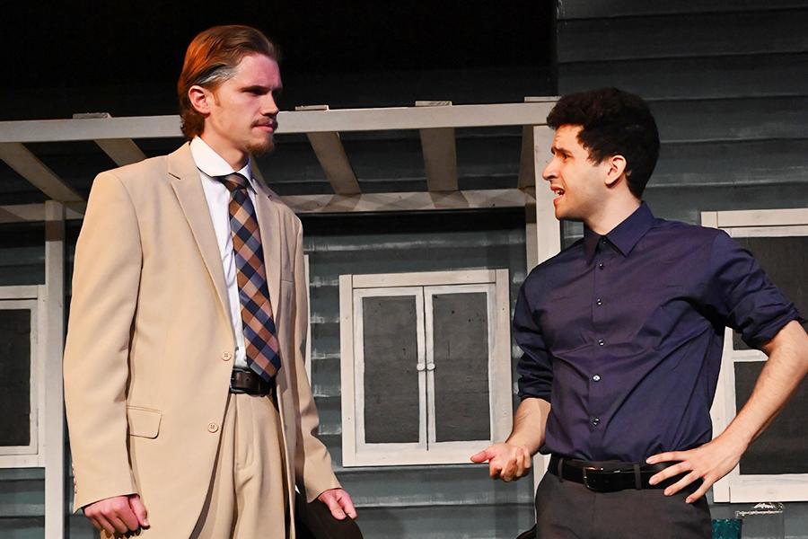 Two men talk outside of a house.