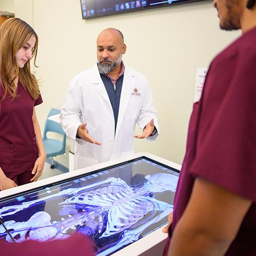 A nursing professor teaches from the anatomy board. 