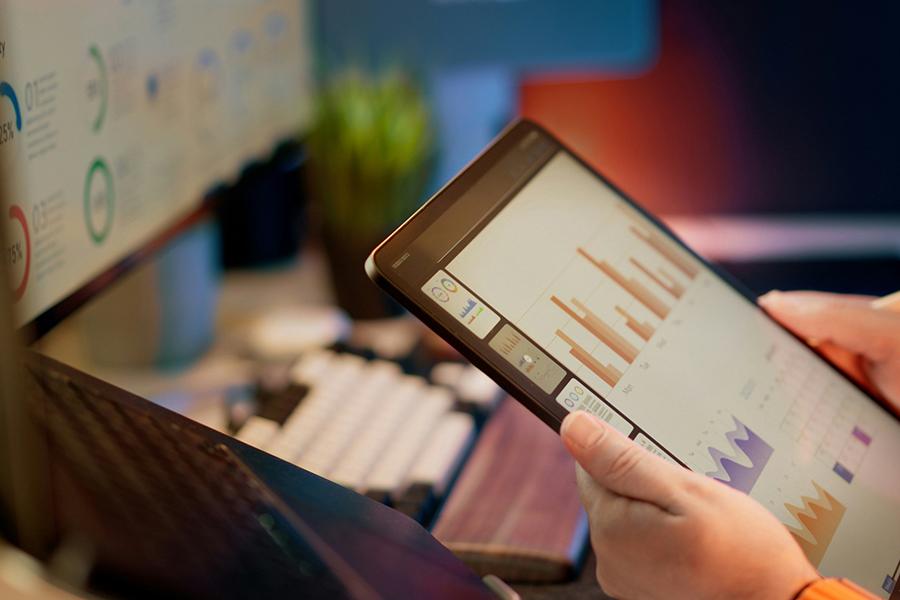 A person working on various dashboards with a computer and a tablet.