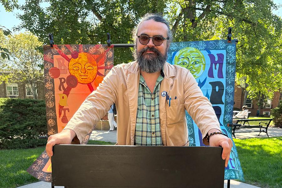 Dr. Jim Robinson standing in the middle at the podium, while the two banners, entitled “Brother Sun, Sister Moon,” are hanging on display in the background.