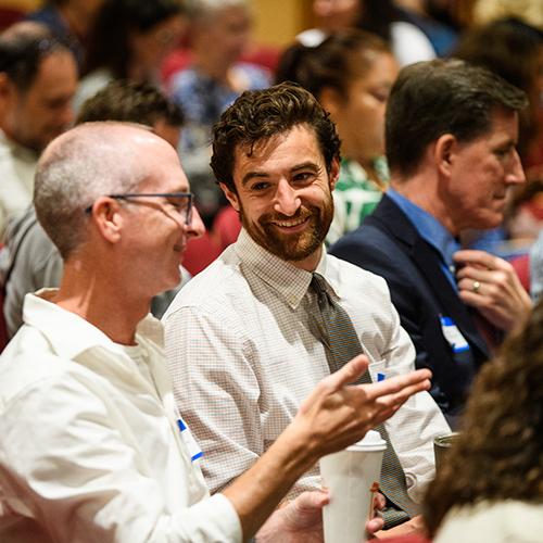Two conference attendees smile and talk.