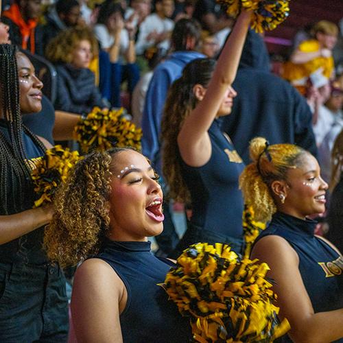 Members of the BSU dance team cheer at a basketball game.