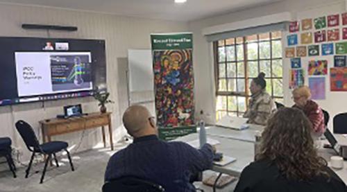 Attendees viewing Br. Kevin presentation with slide showing the visual representation of the potential for Global Temperature rise following the Paris Agreement of 2015.