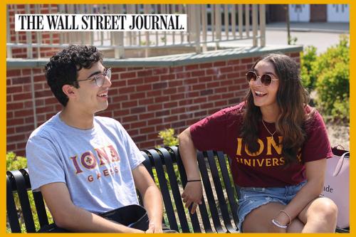 Two students smile on a bench on campus with The Wall Street Journal logo.
