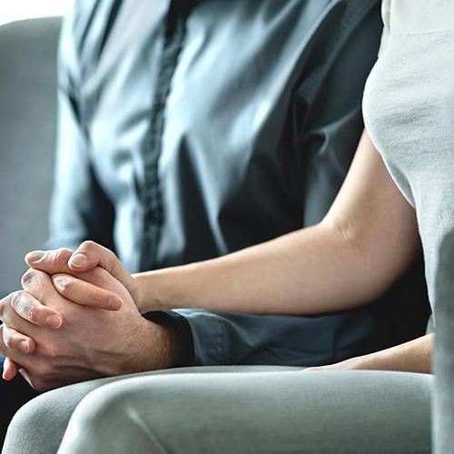 A couple holds hands in an MFT session.