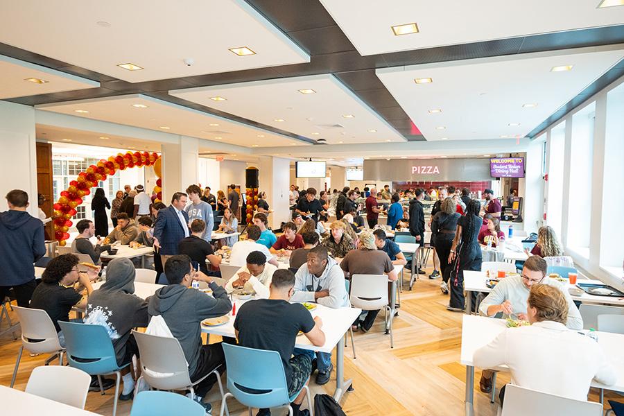 Students and faculty sitting and conversing inside the brand new dining hall, Student Union.