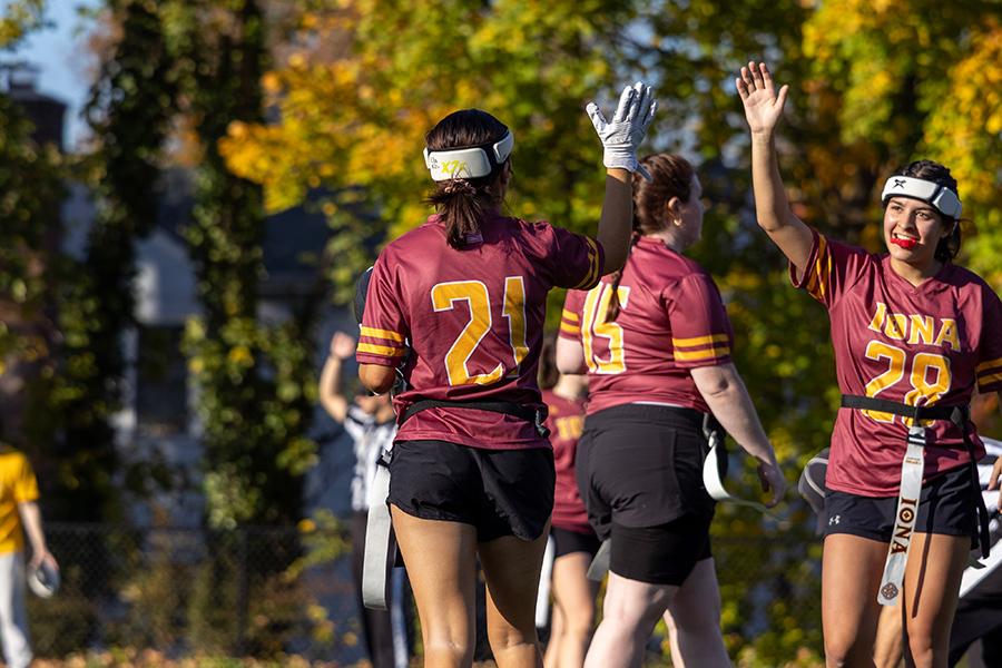 Iona University's Women's Club Flag Football, two players are giving each other a high-five after a play.