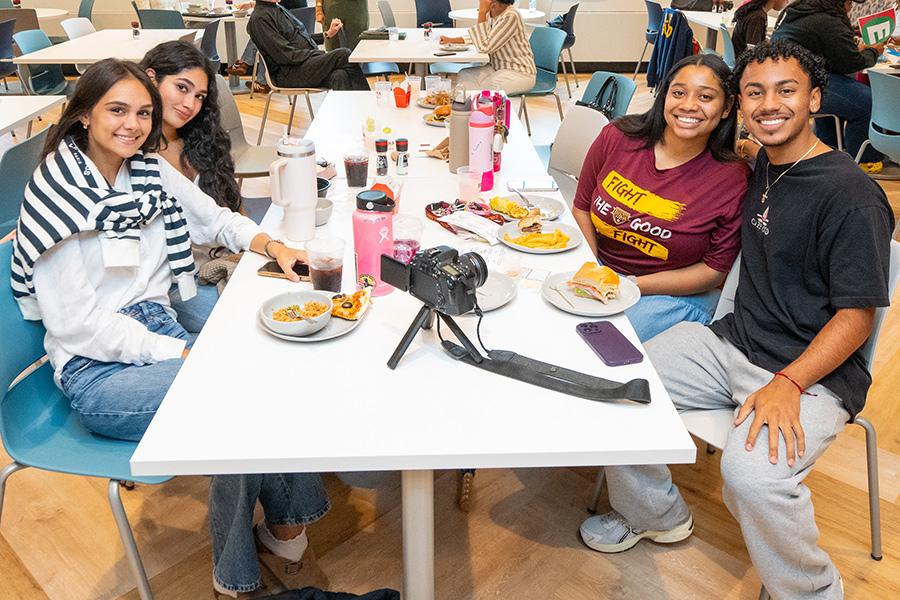 Four students enjoy lunch in the dining hall.