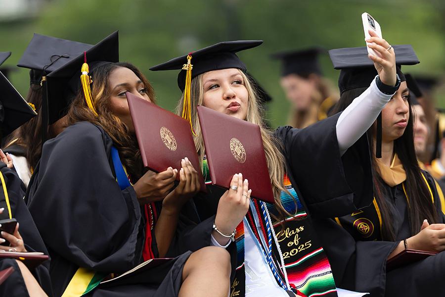 Two grads take a selfie with their degrees.