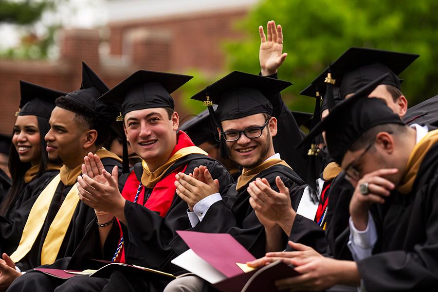 A group of graduates cheer in the crowd.