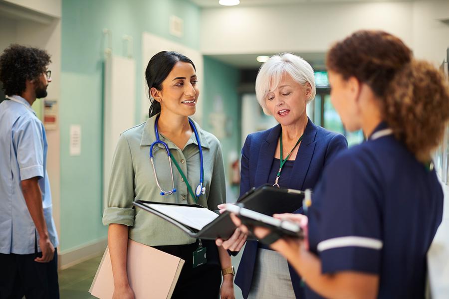 Healthcare leaders work in the hallway of a hospital.