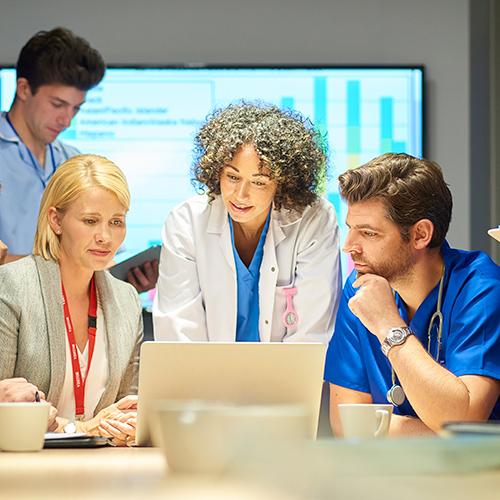 Healthcare administrators and doctors discuss a project in a conference room.