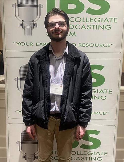 Landon Popovic in front of the IBS awards banner.