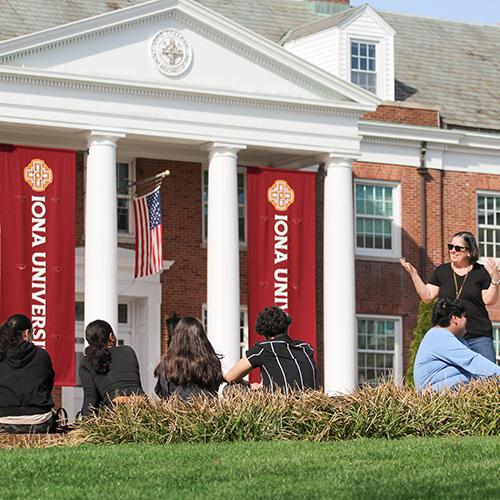Students are outside sitting and facing McSpedon Hall.