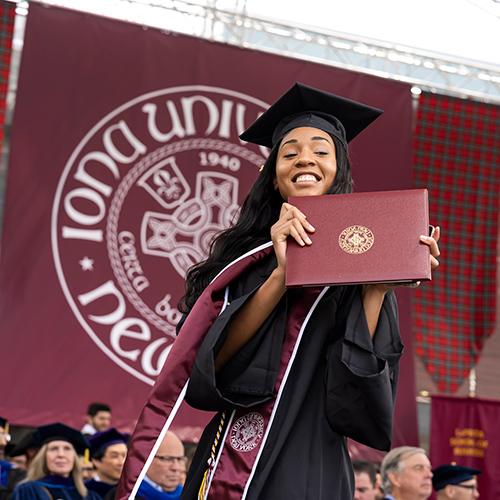 An Iona student holds her diploma on stage during Commencement.