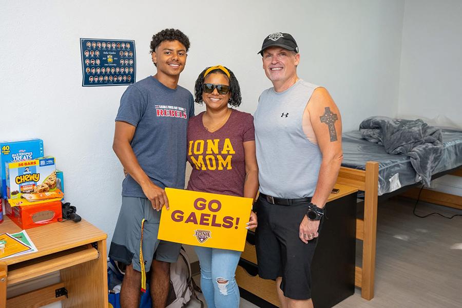 An Iona family holding a Go Gaels sign in their son's room in Bohm Hall.