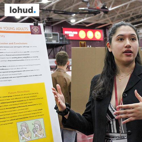 A student presents her work at Iona Scholars Day with the Lohud logo.