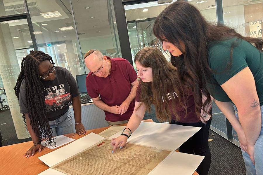 Professor Adam Arenson, with three other students, looking and reading historical documents.