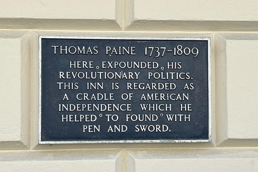 A close-up picture of a plaque on the on the outside structure of the Thomas Paine house.