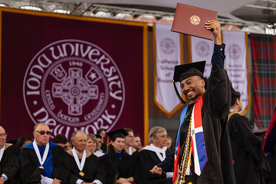 Joe raises his degree above his head on stage.