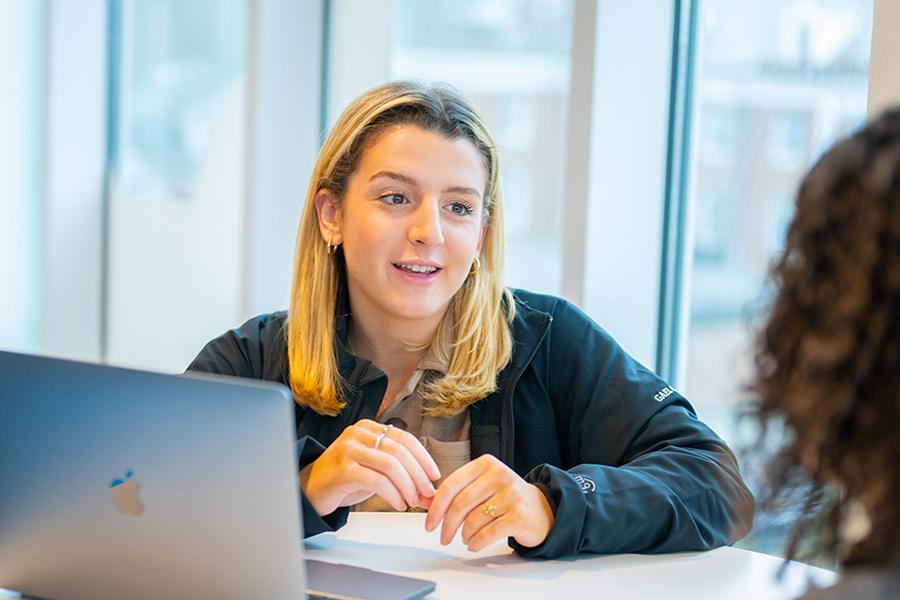 A student in a journalism class practices interviewing a fellow student.