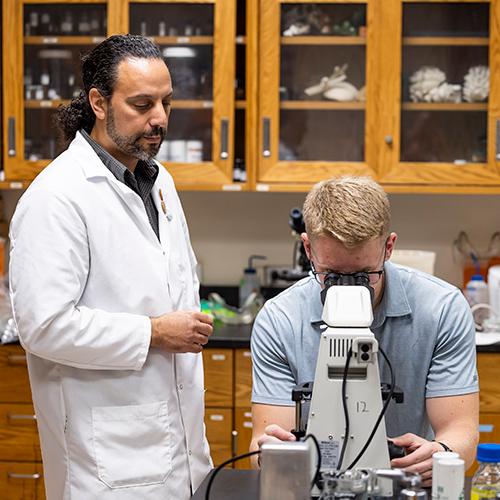 A student and professor perform an experiment in the lab.