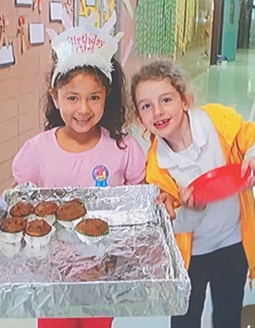 Leila and Grace handing out birthday cupcakes in third grade.