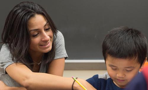 A student teacher works with a young student on his writing skills.