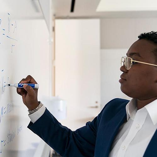 An MBA student writes on a whiteboard.