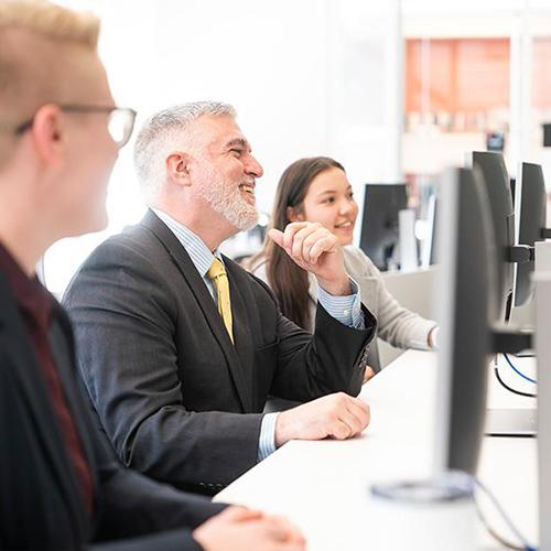 Three students study together in the trading floor room.