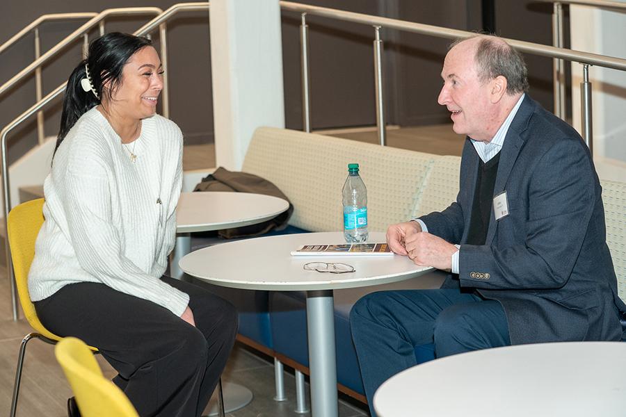 A mentee speaks with her mentor at a table and smiles.