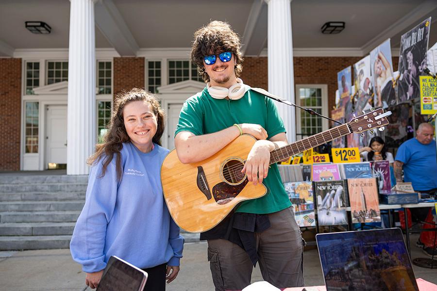Two members of the music club with an acoustic guitar at the Involvement Fair.