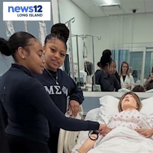 High School students work with a medical mannequin with the News12 logo.
