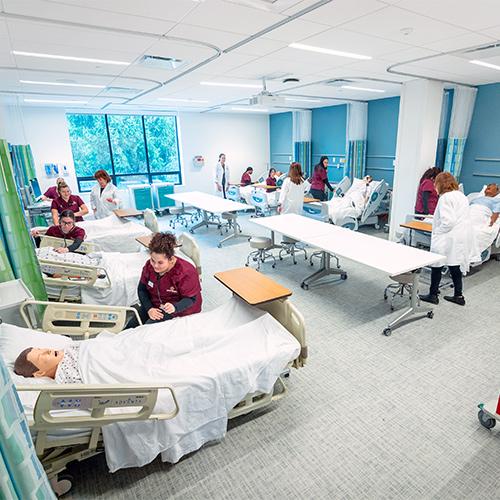 Nursing students work on mannequins in a hosptial-like setting.