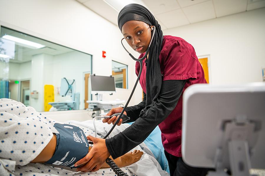 A nursing student practices measuring someone's blood pressure.