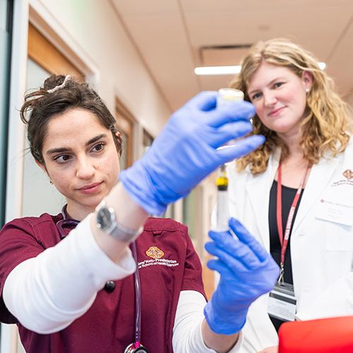 A nursing student practices filling a syringe.