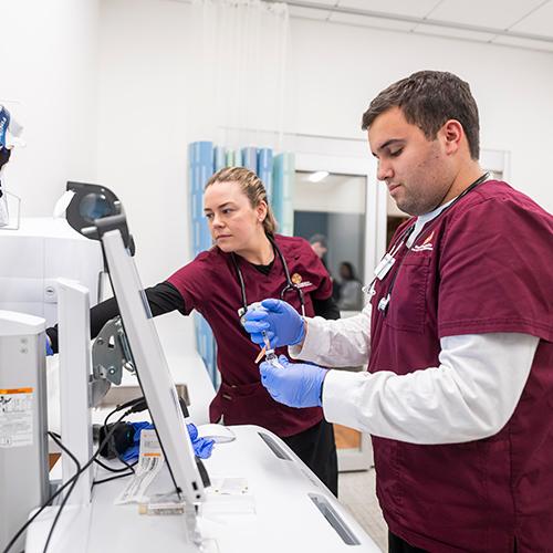 Two nursing students work to prepare a syringe.