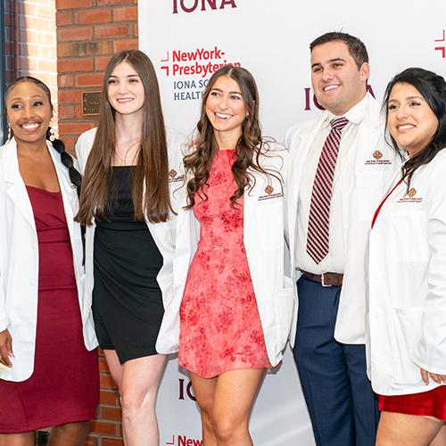 Five graduating nursing students in their white coats.