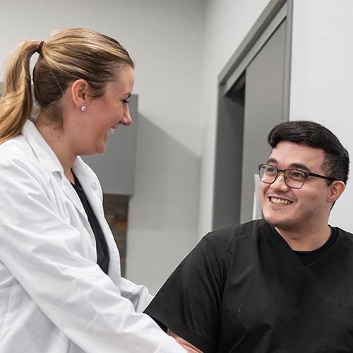 A professor and OT student work together and smile.