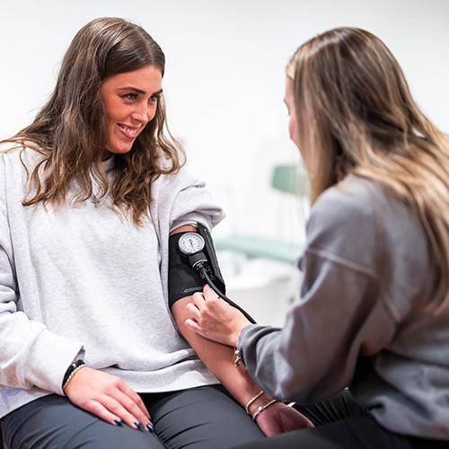 Two OT students practice measuring blood pressure.