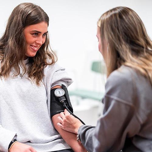 Two health care students practice taking blood pressure.