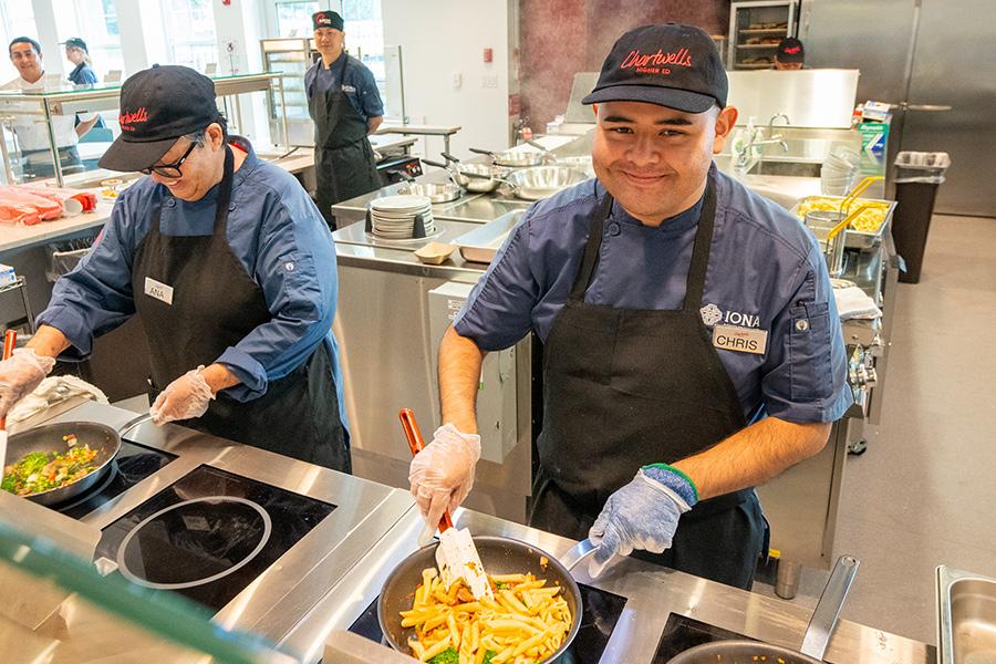 Chefs at the pasta station cook and smile.