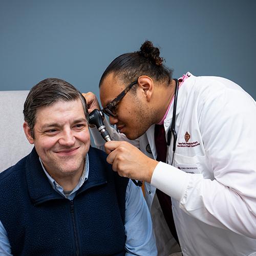 A FNP student practices giving an ear exam.