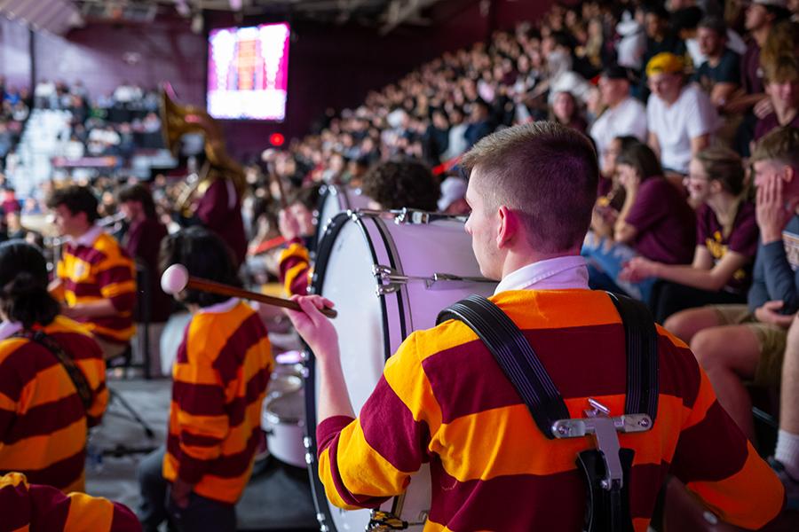 The stand up drummer in the pep band plays at a game.